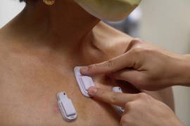 Un trabajador sanitario coloca dispositivos portátiles en el pecho de un paciente adulto.