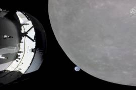 Esta captura de pantalla de NASA TV muestra la cápsula Orion de la NASA, a la izquierda, acercándose a la luna.