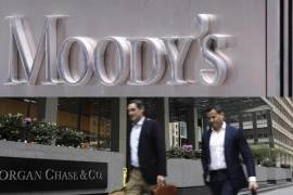 Arriba, logo de la agencia de calificación Moody’s en la fachada de su sede en Nueva York. Abajo, Peatones pasan frente a la oficina de JPMorgan Chase en Park Avenue.