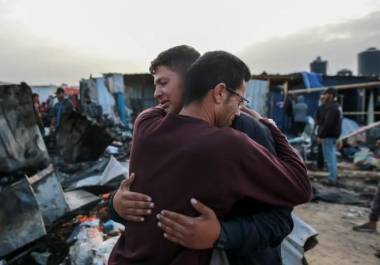 Dos palestinos se abrazan tras el mortal ataque del domingo por la noche en Rafah.