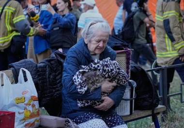 Una mujer mayor sostiene a su gato en brazos, sentada junto a sus pertenencias delante de un edificio residencial que sufrió importantes daños en un ataque nocturno ruso, en Kiev, Ucrania, el 20 de agosto de 2026.