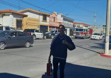 Sergio Olivas, con la casa que ayudó a apagar al fondo, y el extintor en la mano.