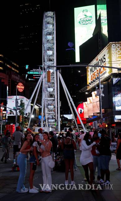 $!La gente toma fotografías frente a la rueda de Times Square de 110 pies (33.5 metros) de altura, una noria que se construyó en Times Square en Nueva York. EFE/EPA/Jason Szenes