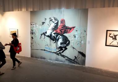 Las personas se paran cerca de la obra de arte “Napoleón cruzando los Alpes” (c) en la exposición ‘El arte de Banksy: sin límites’ en los estudios Ice Palace en Miami. EFE/EPA/Cristobal Herrera-Ulashkevich
