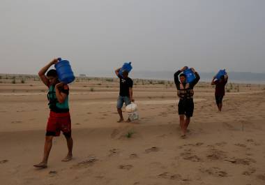 Personas llevan agua desde Humaita hacia la comunidad de Paraizinho, a lo largo de un tramo seco del río Madeira, un afluente del Amazonas, en medio de una sequía, el 8 de septiembre de 2024, en Brasil.
