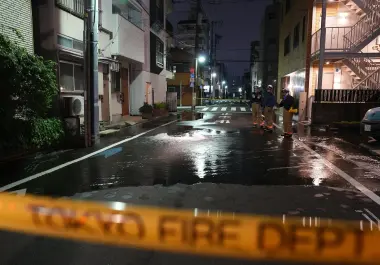 Rescatistas del Departamento de Bomberos de Tokio junto a un camino parcialmente inundado, la madrugada del domingo.