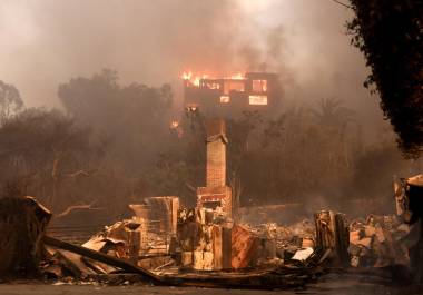 Una casa en llamas y los restos de otra casa quemada en una zona afectada por el incendio forestal de Palisades en Malibú, California. El incendio obligado a la evacuación de al menos 30,000 personas.