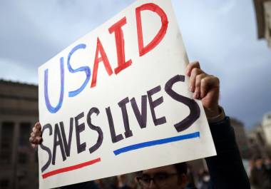 Un manifestante sostiene un cartel frente a la Agencia de Estados Unidos para el Desarrollo Internacional (USAID) en Washington.