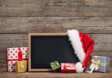 Slate, gift box and santa hat arranged on wooden table during chirtsmas time