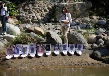 Martha Lucía López sostiene una barca con una foto de su hijo Sergio Melendro López, desaparecido desde la erupción del Nevado del Ruiz, antes de que se lanzaran al río Guali, en Honda, Colombia.