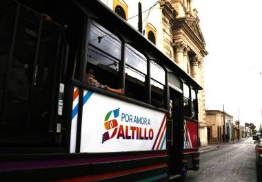 El tranvía recorre calles mojadas del Centro Histórico mientras pasajeros observan la ciudad entre luces y reflejos tras la lluvia.