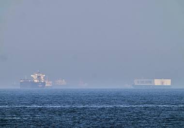Un petrolero (izquierda) y un barco con autos, fondeados en el golfo de Omán, cerca del estrecho de Ormuz, vistos desde las costas de Khor Fakkan, Emiratos Árabes Unidos, informó AP.