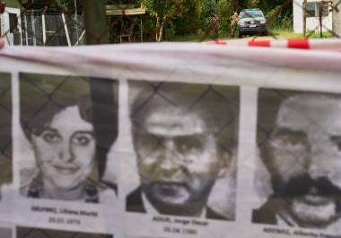 Oficiales del ejército observan desde el interior de la base militar de Campo de Mayo mientras los manifestantes sostienen una pancarta cubierta de imágenes de víctimas de la dictadura militar argentina.