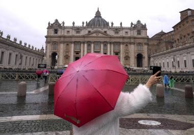 Una mujer toma fotos bajo la lluvia en la plaza de San Pedro en el Vaticano, el sábado 1 de marzo de 2025. FOTO: