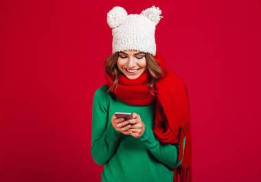 Image of cute pretty young woman wearing hat and scarf. Looking aside chatting by phone.