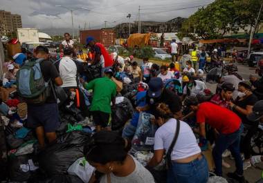 Personas buscan ropa en un campamento frente a edificios colapsados por los terremotos en La Guaira, Venezuela.