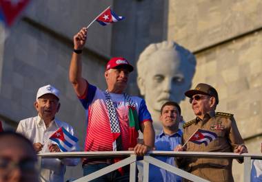 El presidente de Cuba Miguel Diaz-Canel ondea una bandera mientras mira el desfile del Día del Trabajo junto a Raúl Castro, segundo de derecha a izquierda, y Raul Guillermo Rodríguez Castro, nieto de Raúl Castro.