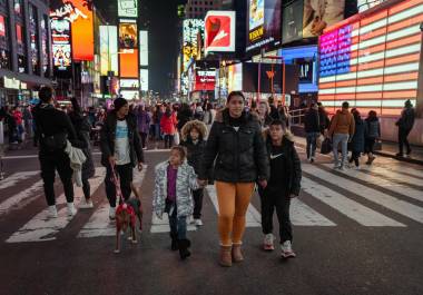 Henry Aguilar y Leivy Ortega con sus hijos, quienes miran asombrados las pantallas iluminadas y los superhéroes disfrazados en Times Square en Nueva York.