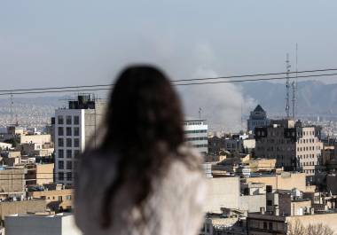 Una mujer observa cómo se eleva el humo tras un ataque con misiles en Teherán, Irán, el lunes 2 de marzo de 2026.