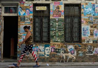 Una mujer pasa junto a un edificio en el que se exhiben fotografías del expresidente cubano Raúl Castro y del expresidente venezolano Nicolás Maduro, en La Habana, Cuba.