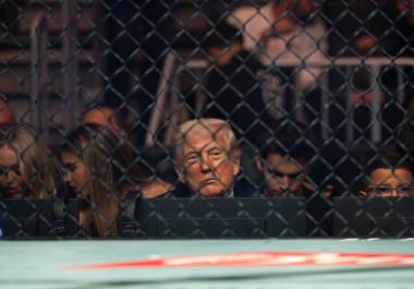 Donald Trump, visto a través de la valla metálica de un evento de la UFC, un reflejo de su aislamiento político y la presión creciente que enfrenta.