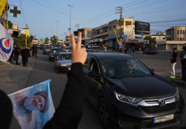 Personas desplazadas regresan a sus casas mientras residentes locales ondean banderas de Hezbollah y una imagen del difunto líder del grupo, Hassan Nasrallah, en Zefta, en el sur de Líbano, el 17 de abril de 2026, tras la entrada en vigor de un alto el fuego con Israel.
