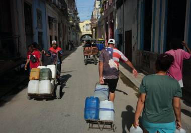 Varias personas transportan agua durante un apagón en La Habana, Cuba, el lunes 3 de agosto de 2026.