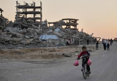 Un niño monta en bicicleta por una calle dañada en el campamento de Al-Shati en la ciudad de Gaza.