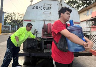 Bryan Pérez carga un bidón de cinco galones de agua hacia su apartamento en el complejo de vivienda pública Villa Kennedy, en San Juan, Puerto Rico, el 10 de junio de 2026.