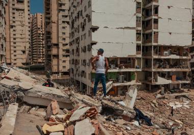 Un hombre observa las viviendas expuestas de edificios enteros que colapsaron completamente, mientras se teme que la crisis política y económica agrave la recuperación.