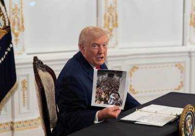 El presidente Donald Trump sostiene una fotografía mientras se dirige a reporteros tras hablar con las tropas por video desde su residencia de Mar-a-Lago en Palm Beach, Florida. FOTO: AP / Alex Brandon