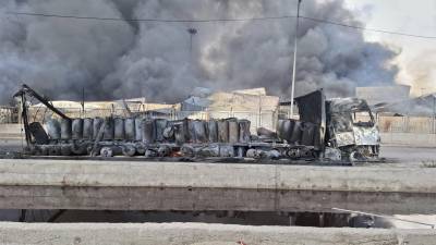 El humo se eleva en el fondo junto a los restos destrozados de un camión, el domingo 27 de abril de 2025, después de una enorme explosión en un puerto cerca de la ciudad portuaria sureña de Bandar Abbas, Irán, el sábado. FOTO: