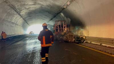 Personal de emergencia combate las llamas en el lugar del accidente mientras se interrumpe la circulación en ambos sentidos de la carretera 57.