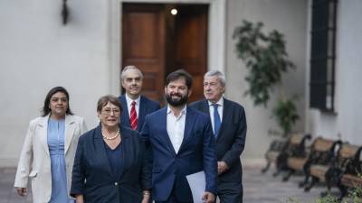 El mandatario Gabriel Boric (c), junto a la expresidenta Michelle Bachelet (2i) caminando en el palacio de La Moneda, en Santiago, Chile.