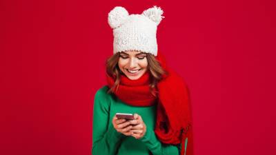 Image of cute pretty young woman wearing hat and scarf. Looking aside chatting by phone.