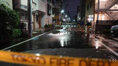 Rescatistas del Departamento de Bomberos de Tokio junto a un camino parcialmente inundado, la madrugada del domingo.