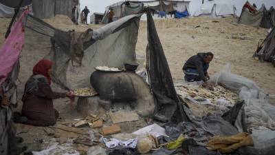 Mona Al-Zebda, desplazada de Ciudad de Gaza, hornea pan en un campamento de tiendas para palestinos desplazados en Muwasi, Rafah, sur de la Franja de Gaza, lunes 24 de febrero de 2025. FOTO: