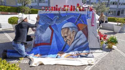 El pintor mexicano Roberto Márquez coloca un retrato del papa Francisco afuera del Hospital Gemelli de Roma,, donde el pontífice se encuentra hospitalizado. FOTO: