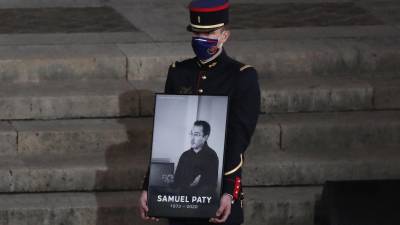 Un guardia republicano sostiene un retrato de Samuel Paty en el patio de la Universidad de la Sorbona durante un evento conmemorativo nacional, el miércoles 21 de octubre de 2020 en París.