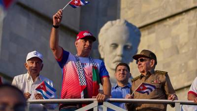El presidente de Cuba Miguel Diaz-Canel ondea una bandera mientras mira el desfile del Día del Trabajo junto a Raúl Castro, segundo de derecha a izquierda, y Raul Guillermo Rodríguez Castro, nieto de Raúl Castro.