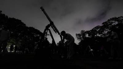 Una niña mira la luna a través de un telescopio en Caracas, Venezuela, el domingo 15 de mayo de 2022.