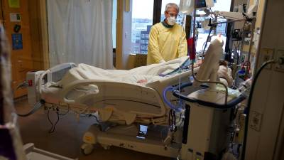 Steve Grove, capellán del Centro Médico del Condado Hennepin, ora en el cuarto de un paciente con COVID-19, el 10 de diciembre de 2021, en Minneapolis.