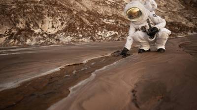 Representación de un astronauta recogiendo una roca durante una misión espacial en otro planeta.