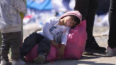 Un niño descansa sobre una bolsa mientras es procesado por la Patrulla Fronteriza de Estados Unidos entre las dos vallas fronterizas en la frontera sur de Estados Unidos con México, en San Diego, California.