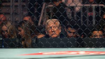 Donald Trump, visto a través de la valla metálica de un evento de la UFC, un reflejo de su aislamiento político y la presión creciente que enfrenta.