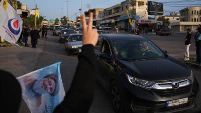 Personas desplazadas regresan a sus casas mientras residentes locales ondean banderas de Hezbollah y una imagen del difunto líder del grupo, Hassan Nasrallah, en Zefta, en el sur de Líbano, el 17 de abril de 2026, tras la entrada en vigor de un alto el fuego con Israel.