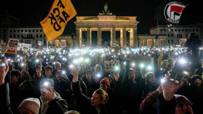 Una multitud sostiene sus teléfonos con la lámpara encendida mientras protestan contra el partido político de extrema derecha, Alternativa para Alemania o AfD por sus siglas en alemán, frente a la Puerta de Brandeburgo, en Berlín. FOTO: