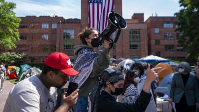 Activistas pro palestinos reaccionan ante el despliegue de una gran bandera estadounidense en el campamento de manifestantes en la Universidad George Washington (GWU) en Washington, DC.