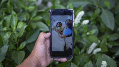 Mynor Cardona muestra una foto en su teléfono celular de su hija, Yenifer Yulisa Cardona Tomás, en el hospital mientras recibe una visita, en la Ciudad de Guatemala.