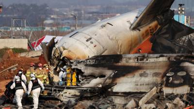 Los bomberos trabajan en los restos del avión Jeju Air en el Aeropuerto Internacional de Muan, 29 de diciembre de 2024. Las autoridades elevaron a 179 la cifra oficial de muertos en el accidente del avión comercial que se salió de la pista y chocó contra un vallado tras aterrizar.